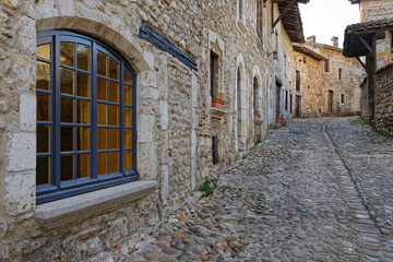 Fototapeta na wymiar PEROUGES, FRANCE, February 23, 2021 : A street of the old medieval town. The town was restored and houses were saved in the beginning of 20th century and is now a popular tourist attraction.