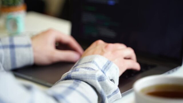 A man works with a laptop, types text on the keyboard, working office