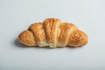 One whole fresh delicious croissant on a white background