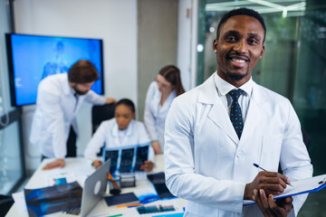 African American doctor looking at the camera. behind him, docto - obrazy, fototapety, plakaty