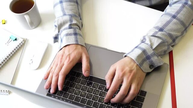 A man works with a laptop, types text on the keyboard, working office