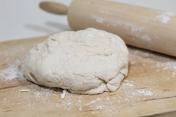 Dough in a wooden table with a wooden pin