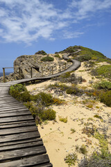 Fototapeta na wymiar Winding wooden path going up the hill in Robberg Nature Reserve, Plettenberg Bay, South Africa. The sky is blue.