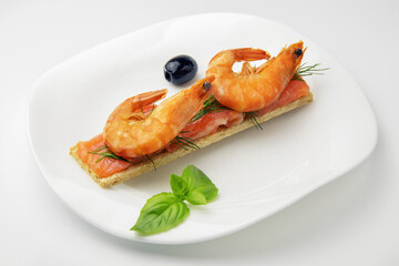 diet bread with slices of red fish and shrimp with sprig of dill, olives in the white plate on white background, healthy food