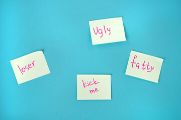Children's bullying at school. Offensive stickers on a blue background.ugly. loser, kick me. fatty