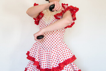 Detalle de una mujer española vestida con un vestido de lunares rojos de flamenca tocando las...