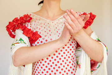 Detalle de una mujer española vestida con un vestido de lunares rojos de flamenca y un mantón de...