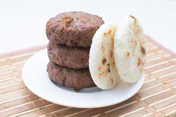 Seasoned meatloaf served with corn arepa on white wooden background