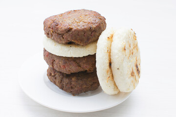 Seasoned meatloaf served with corn arepa on white wooden background