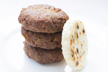 Seasoned meatloaf served with corn arepa on white wooden background