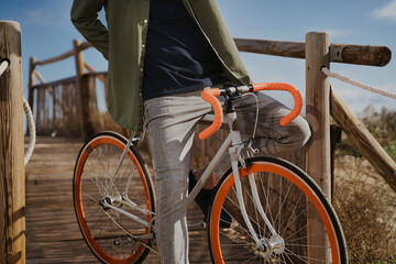 Fototapeta premium Unrecognized man riding cool orange bike in the coast.