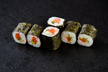 Sushi roll sea food on black background. Sushi delivery from the restaurant. Fresh delicious Japanese sushi with avocado, cucumber, shrimp and caviar on dark background
