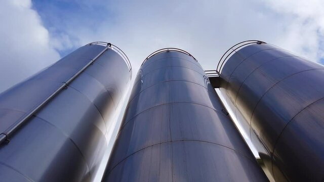 Large metal silo for storing raw material. Modern industrial plant.
