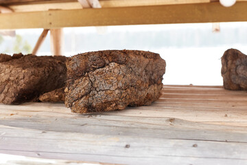 Chunk of peat piled up for drying on wooden shelf. Peat production
