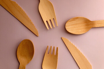 Wooden spoons, forks and knives on pastel pink background. Top view.