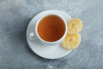 A cup of aroma tea with dried pineapple on a dark background