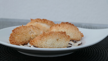 close-up of lush coconut macaroon dumplings on a white plate with coconut chips