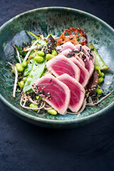 Modern Style traditionelles japanisches gebratenes Tunfisch Tataki Steak mit Soba Nudeln und Stir-Fried Gemüse serviert als close-up auf einem Nordic Design Teller