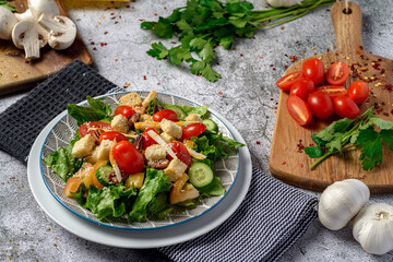 Fresh salad with lettuce tomato cucumber mushroom cheese and parsley top view over gray stone table 