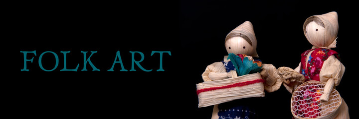 Set of straw souvenir dolls in national costumes isolated on black background