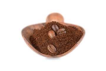Ground coffee and grains in a wooden spoon isolated on white background.