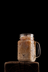 Cold coffee with ice cream on dark background. Refreshing, invigorating cocktail on the rocks. Vertical orientation, copy space