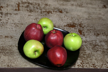 Red and green apples on the plate on the table