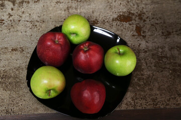 Red and green apples on the plate on the table