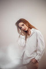 Obraz premium Businesswoman confident portrait. Fashion shoot of young sexy in white studio street style. Fashion photo. Caucasian female with long hair. Close-up portrait of a beautiful girl of the European race.