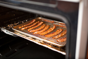 A view of a baking sheet full of bacon inside an oven.