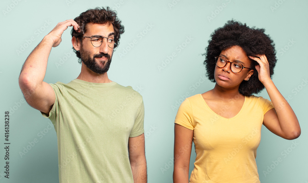 Wall mural multiracial couple of friends feeling puzzled and confused, scratching head and looking to the side