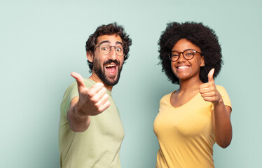 multiracial couple of friends feeling proud, carefree, confident and happy, smiling positively with...