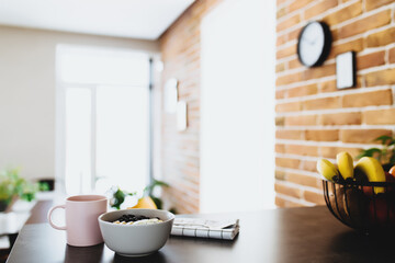 Pink coffee cup, bowl with chopped fruits and blueberries, spoon in kitchen