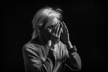 Classic black-and-white dramatic portrait of elderly blonde woman in Studio on black background