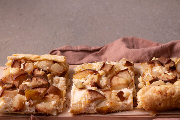 Pieces of pie with cheese and pears on a wooden board with copy space.