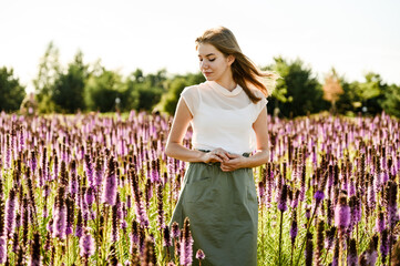 beautiful girl in a flower field at sunset of the day. wildflowers. happy woman. spring walk