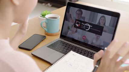 Back rear view young asian woman employee work from home using computer notebook videocall meeting...