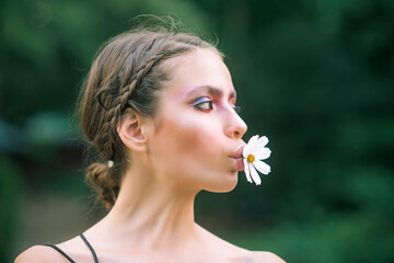 Spring woman with daisy flower in mouth. Beauty, nature concept. Fashion look, makeup. Youth, flowering, blossom, bloom.