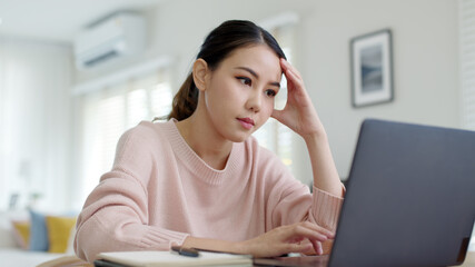 Back rear view young asian woman employee work from home using computer notebook videocall meeting...