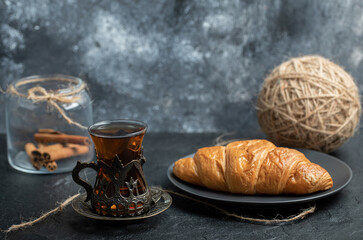 A glass jar full of cinnamon sticks with cup of tea