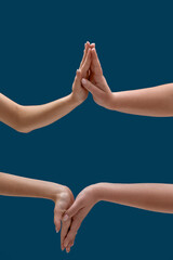 Close up of two women holding or measuring hands, touching each other palms isolated over blue background
