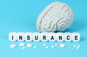 Cubes lie on the table among the pills and imitation of the brain. The text on the dice - INSURANCE