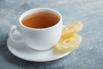 A cup of aroma tea with dried pineapple on a dark background