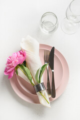 Romantic table setting with pink peony for festive party on white table. Vertical format. View from above.