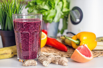 Wellness  smoothie of greens and wild berries in a transparent glass on the kitchen table