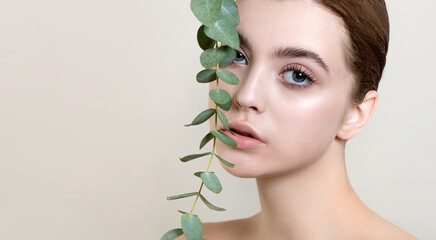 Portrait of beauty model with natural nude makeup with eucalyptus leaf branch.