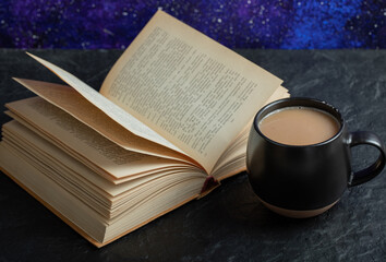 A cup of coffee with book on a dark background