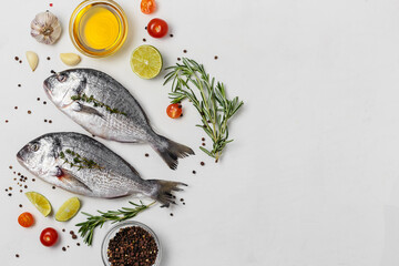 Fresh fish dorado fish on white table with ingredients for cooking