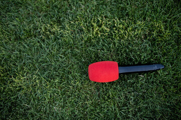 Black - red handheld wireless Mic laid down on the green grass for all type of event activities. microphone for announcing outdoor sport and announcement concept design with copy space