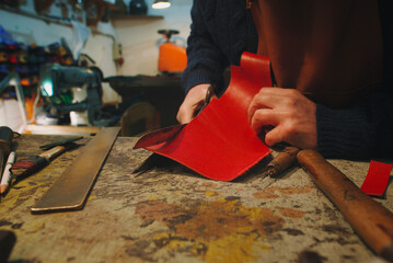 hands of craftsman cut piece of red leather